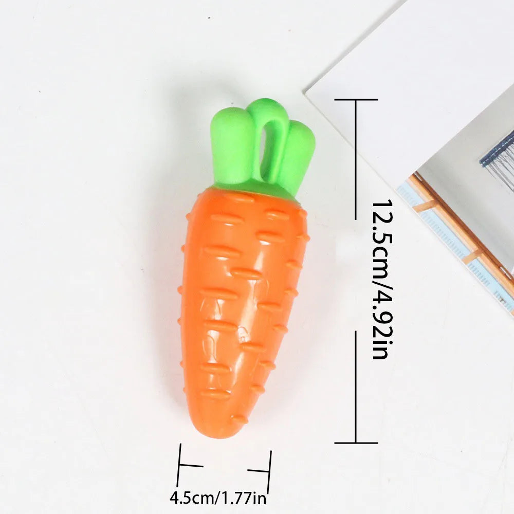 An orange carrot shaped squeaky chew toy for dogs with a green handle, shown next to a ruler.