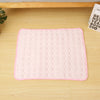 A pink quilted cooling mat designed for pet beds, placed on a light wooden surface.