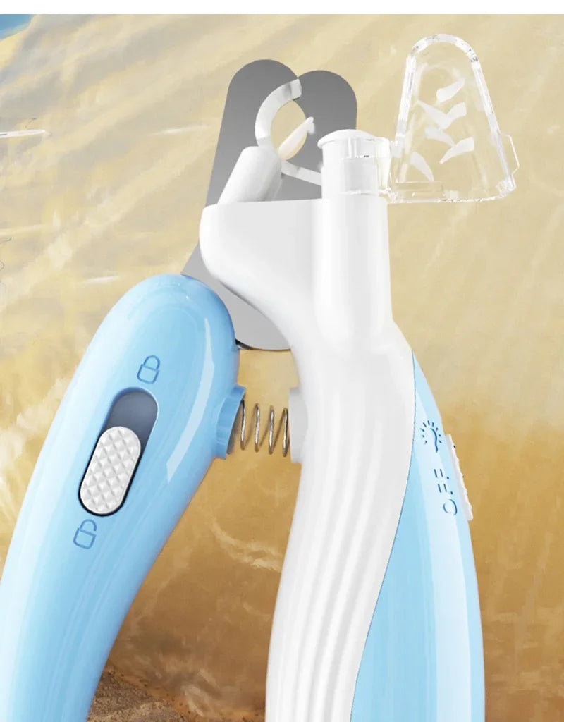 A close-up of a light blue pet nail clipper and its accessory, showing the clippers and a clear plastic tool against a sandy 