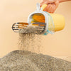 A hand is using a stainless steel cat litter shovel with a clear refill bag to pour dry litter onto a pile of granular materi