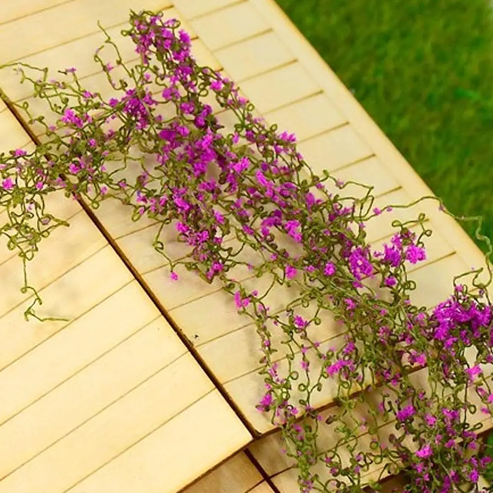Eine Rebe mit lila Blüten wächst über einer hellen Holzoberfläche.