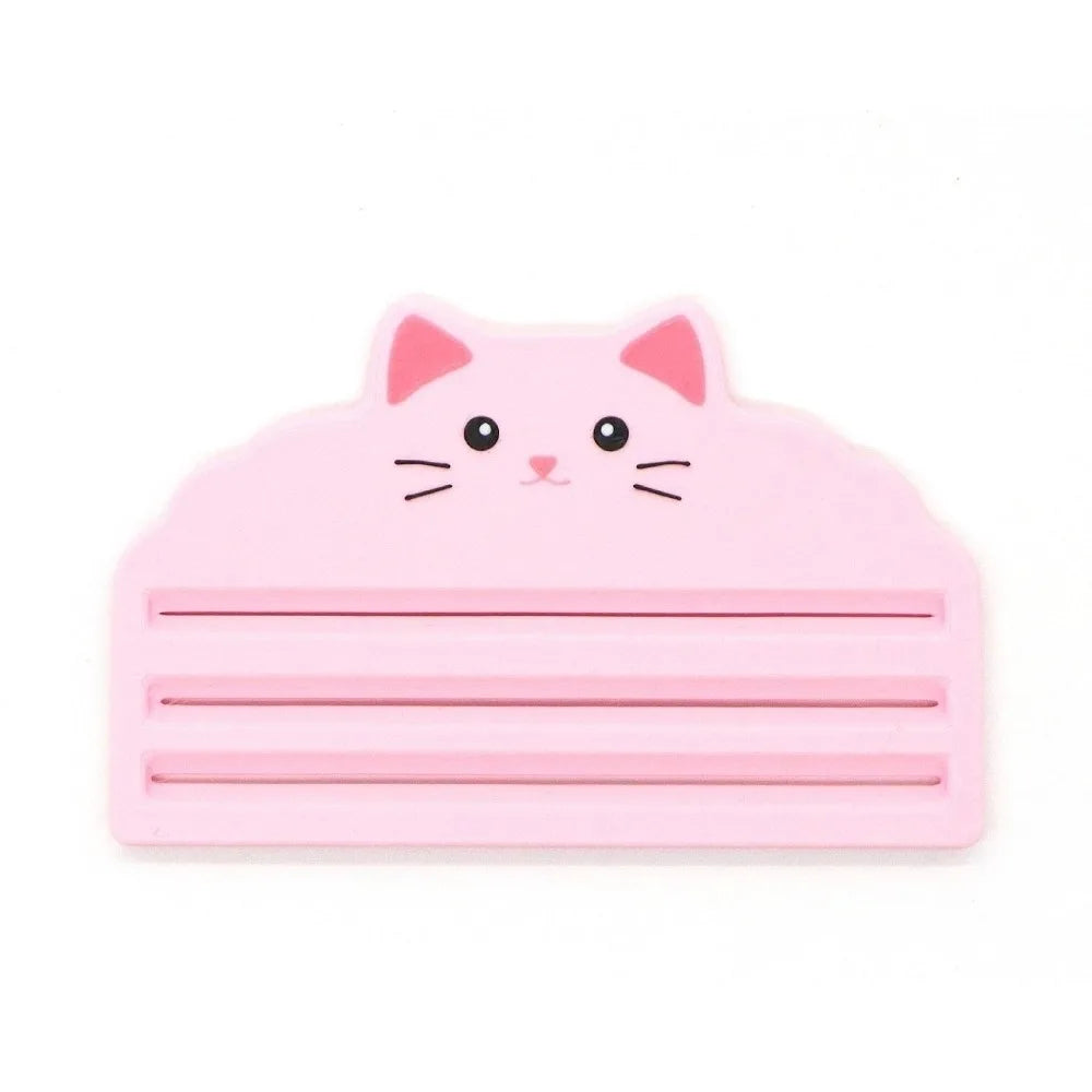 A pink reusable cat food pouch scraper shaped like a cat's head.