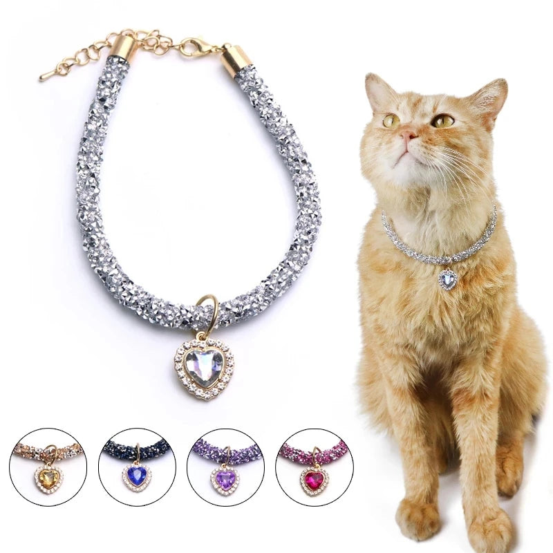 A gold chain collar with a sparkling crystal heart pendant and various colored gemstone options displayed next to an orange c