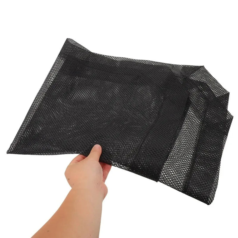 A hand is holding a black breathable mesh replacement cover for an elevated pet bed.
