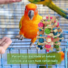 Ein leuchtend orange Papagei sitzt auf einem Drahtgeflecht, umgeben von natürlichen Rattanbällen als Papageitoy