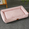 A pink waterproof orthopedic dog bed with a removable cover lying on a gray carpet.