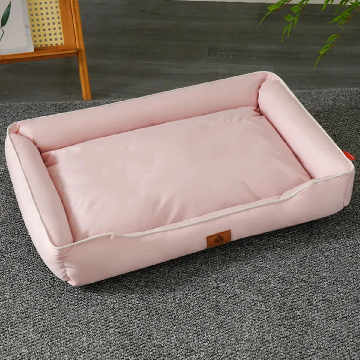 A pink waterproof orthopedic dog bed with a removable cover lying on a gray carpet.