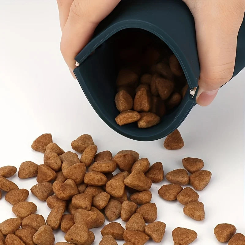 A hand is holding a dark silicone pouch filled with brown dog treats.