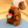 A brown capybara plush toy with an orange flower on its head and a green leaf attached to its mouth.