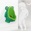 Un entrenador de entrenamiento para el inodoro en forma de rana verde junto a la silueta de un niño.