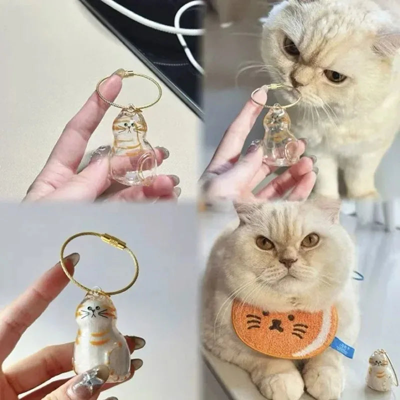 Ingwerkatze Haustier-Aufbewahrungsschlüsselanhänger mit kleiner Katzenfigur, gehalten von einer Person und neben einer lebend