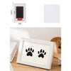 A white wooden photo frame with a black paw print design, shown in a close-up on a wooden surface.