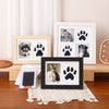 A wooden photo frame displaying a cat and dog paw print, set in a kit with a small black display box.