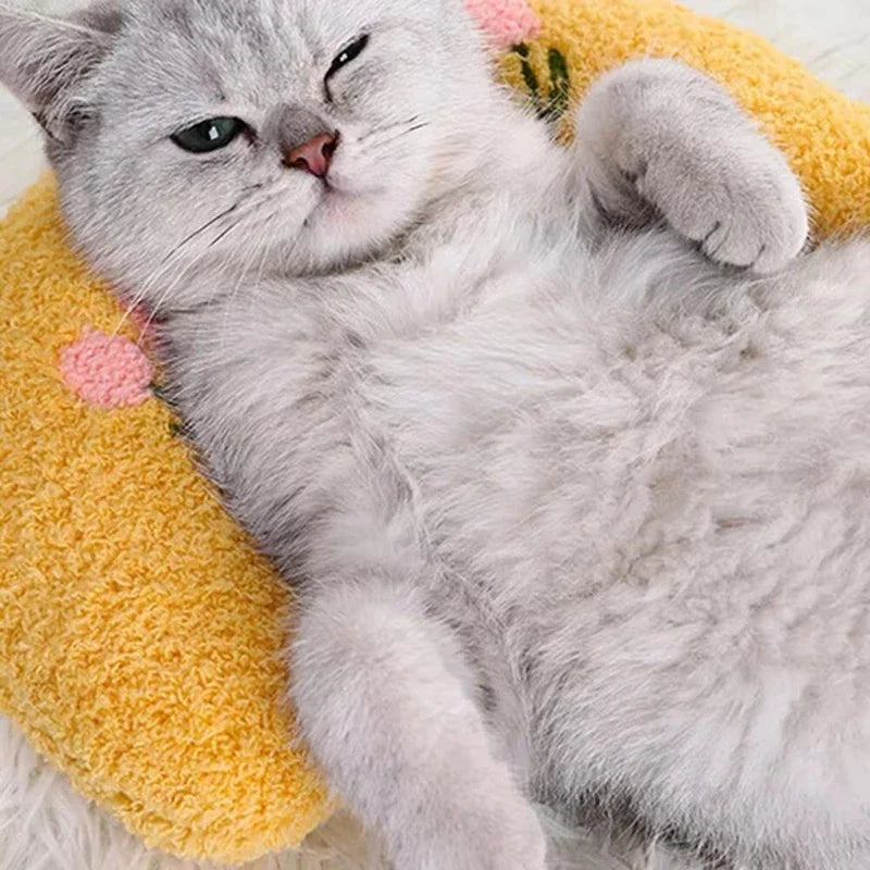 Un chaton gris et duveteux se détend sur un coussin d'animal jaune.