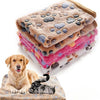 A stack of soft fleece pet bed mats covers, with a golden retriever and a black cat resting nearby.