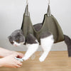 Un chat se repose dans une hamac de toilettage verte pendant qu'une personne utilise un outil sur sa patte.