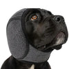 A black dog wearing gray pet noise reduction ear muffs.