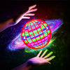 A hand is holding a glowing, spherical LED flying boomerang ball with colorful lights against a dark, cosmic background.