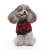 A fluffy gray poodle wearing a red plaid shirt and black sweater.