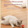 A white cat is interacting with an orange silicone ball toy on a wooden floor.