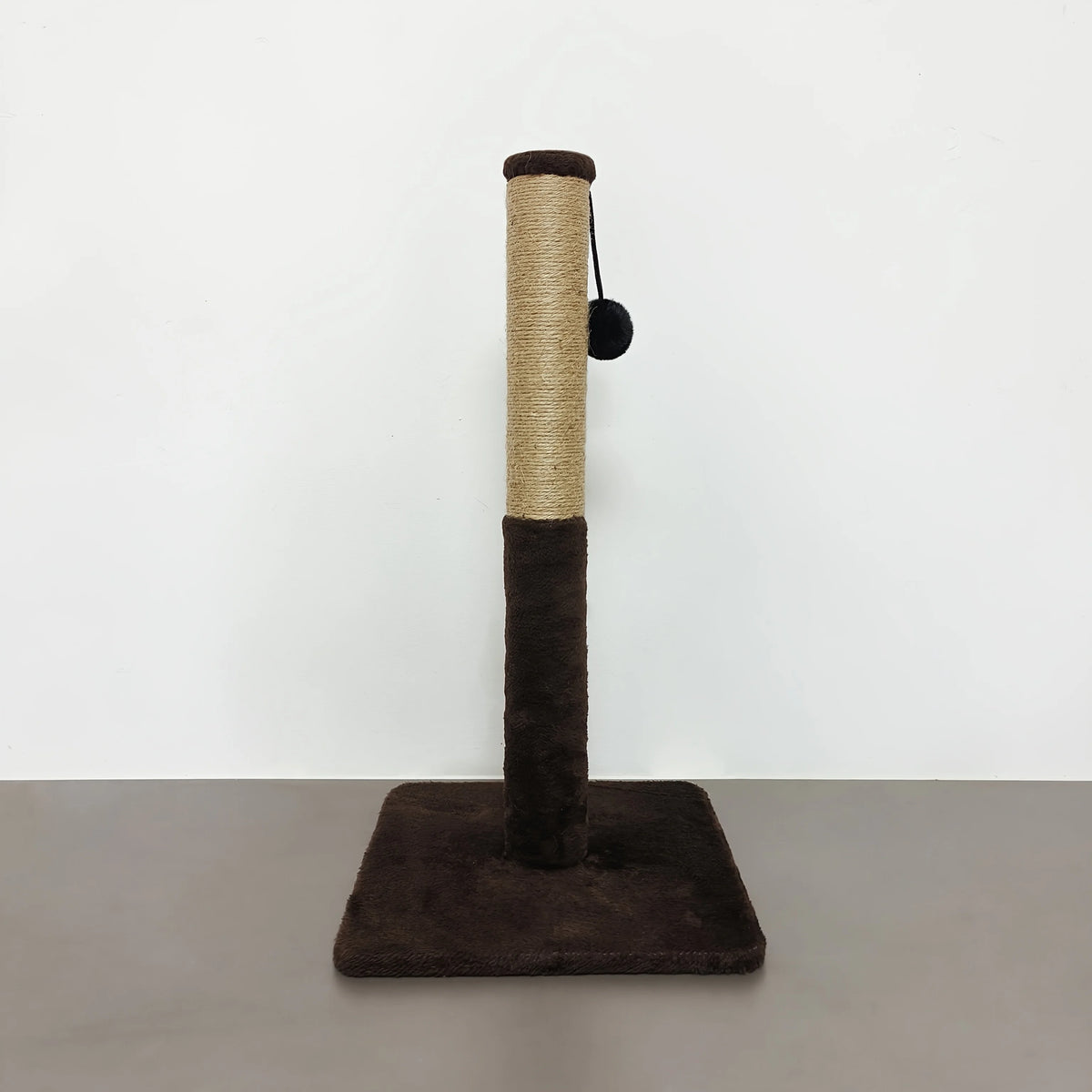 A tall, cylindrical sisal cat scratching post with a dark felt ball attached, set on a gray surface.