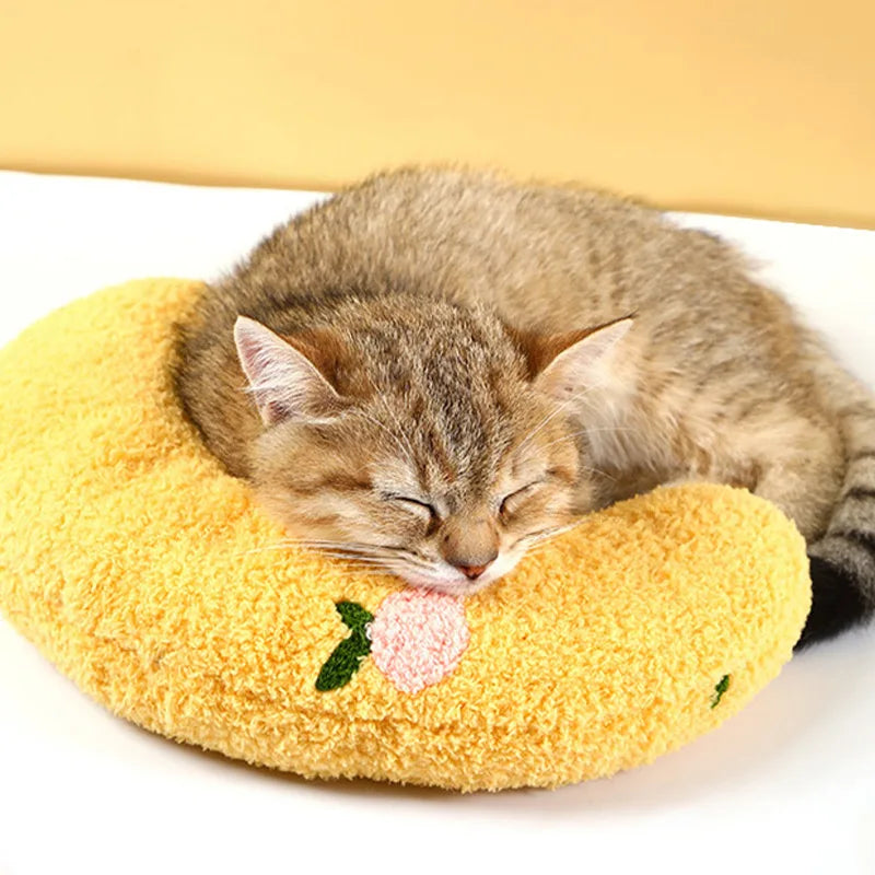 Un chaton tigré dort paisiblement sur un oreiller de compagnie jaune et duveteux.