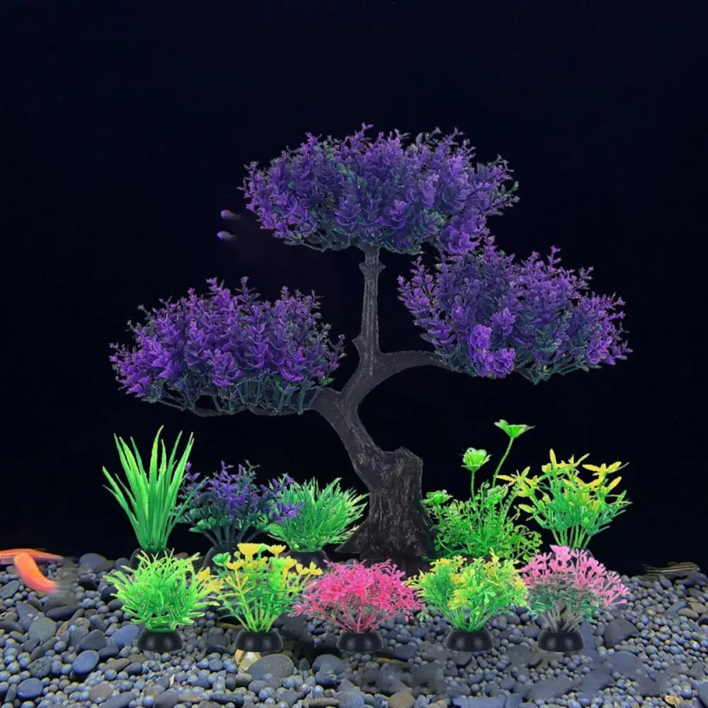 Exhibición de plantas de acuario artificiales realistas en tonos verdes, rosas y morados sobre una superficie de grava oscura