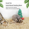 A small gray pet is eating from a natural solid wood feeding bowl on a light-colored surface.
