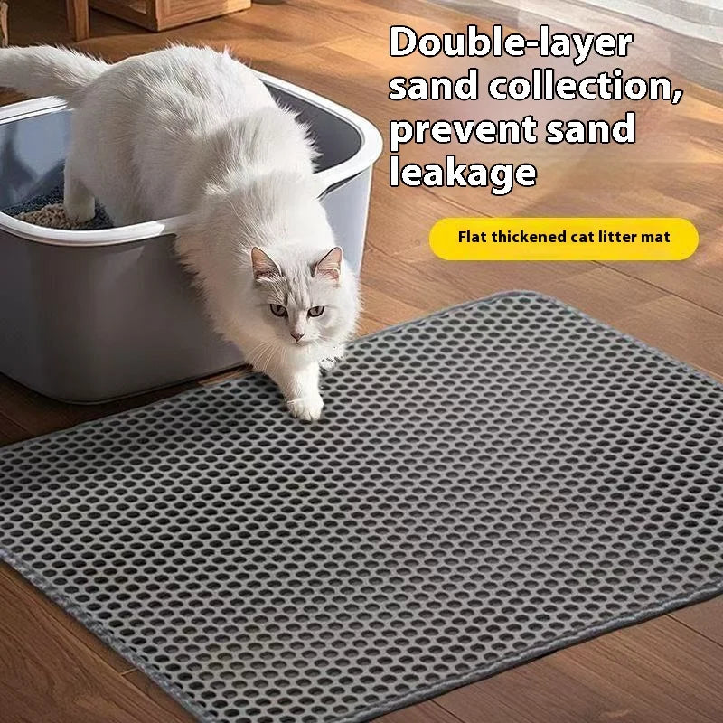Eine weiße Katze sitzt auf einer grauen, verdickten Katzenstreumatte, die Sandleckage verhindert.