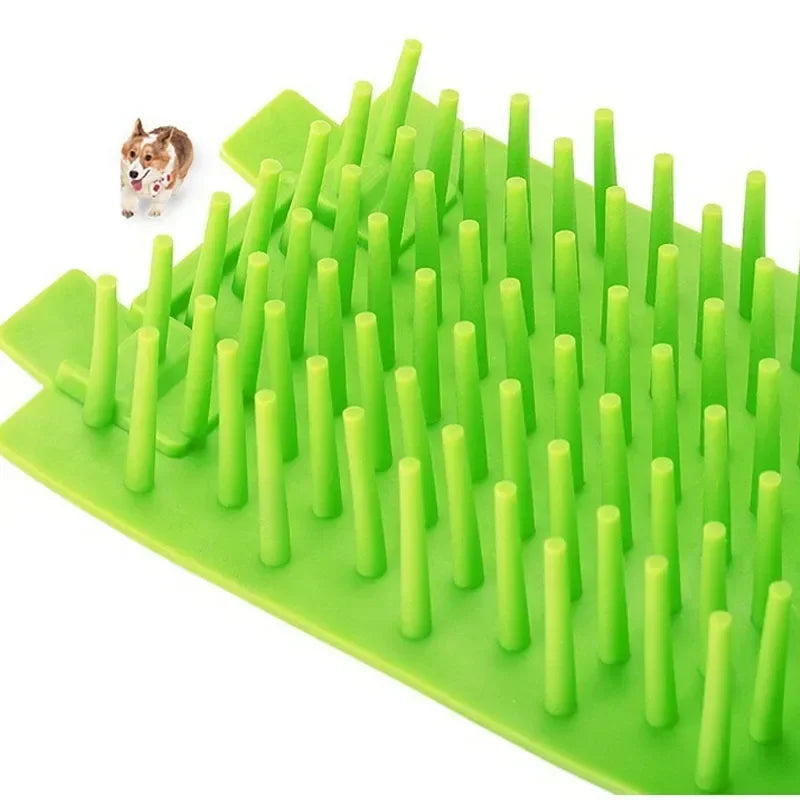 A green silicone pet paw cleaner tool with numerous cylindrical bristles is shown next to a small dog.