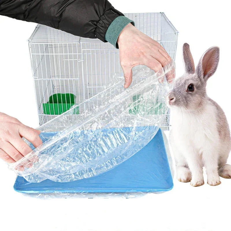 Eine Hand benutzt eine Plastikmatte, um den Boden eines Drahtkäfigs mit einem Kaninchen zu reinigen.