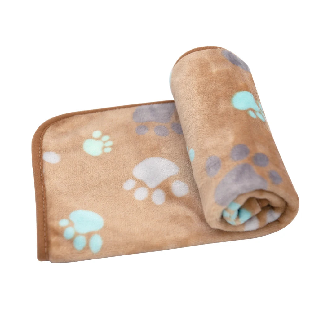 A rolled-up, tan pet blanket with light blue paw prints is shown.