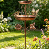 Una fuente de bronce vintage montada en un soporte, con un pájaro pequeño bebiendo agua en un jardín.