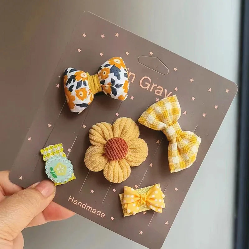 Una mano sostiene una tarjeta marrón con cinco lazos de moda hechos a mano en diversos patrones florales y a rayas.