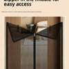A black foldable metal mesh pet gate is shown installed in a wooden enclosure for easy access.