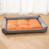 A gray pet sofa bed with an orange corduroy cushion placed on a light wooden floor.