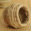 A natural straw bird nest for pet avians, woven into a round, textured shape.