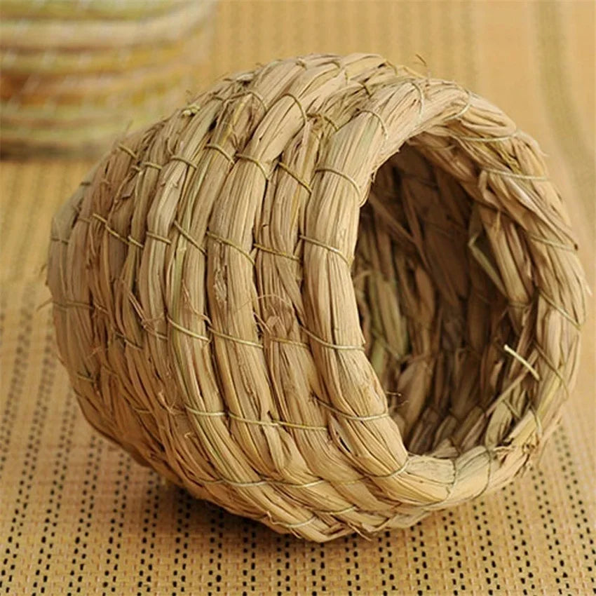 A natural straw bird nest for pet avians, woven into a round, textured shape.