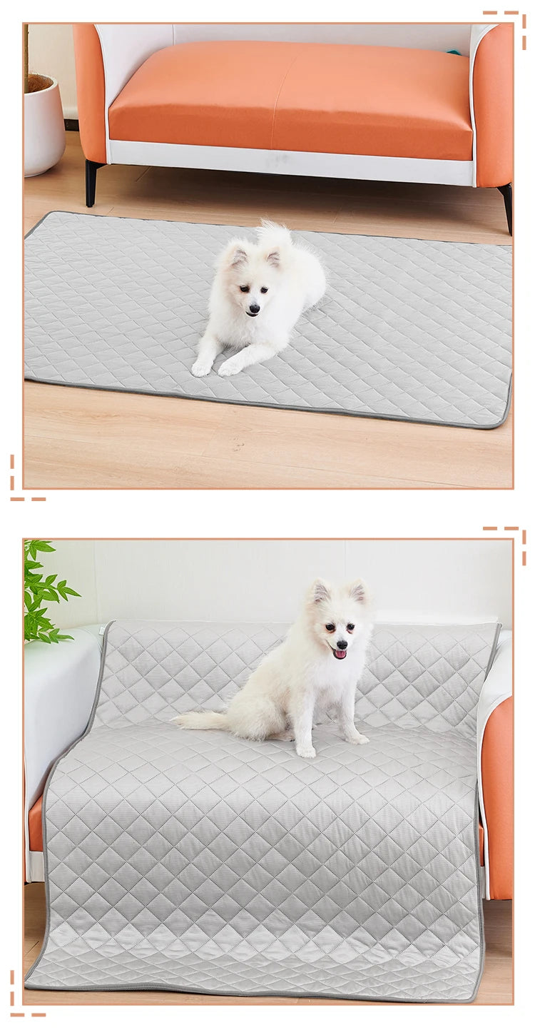 A fluffy white dog is lying on a gray quilted washable cooling mat placed on a wooden floor and a sofa.
