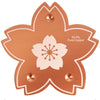 A round, copper-colored cleaning disc with a white flower design and four mounting holes.