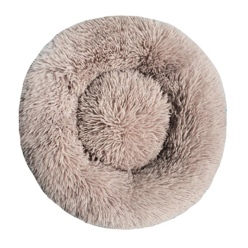 A round, fluffy pet bed with a removable washable cover in a light beige color.