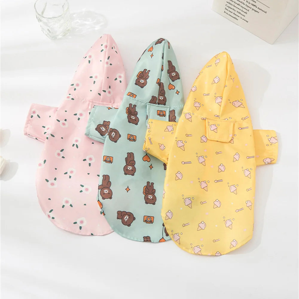 A set of three cartoon printed dog raincoats in pink, mint green, and yellow for small breeds.