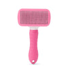 A pink pet hair removal brush with massage pins and a white handle.