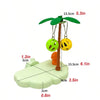 A tropical bird play perch featuring a wooden branch and hanging yellow and green toy balls on a light green base.