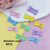 Eight bone-shaped hair clips in various pastel colors are displayed on a white surface.