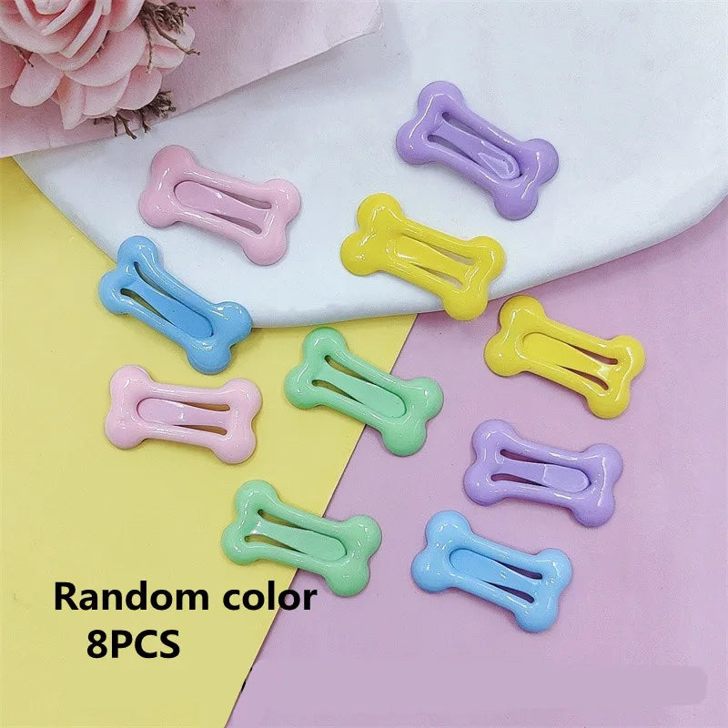 Eight bone-shaped hair clips in various pastel colors are displayed on a white surface.