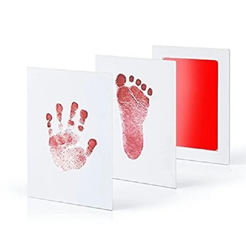 White framed art showing a reddish handprint and footprint on a white background.