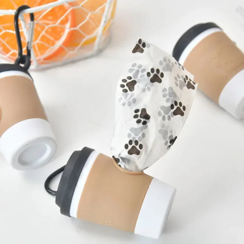 A portable pet poop trash can dispenser with a cardboard cover and beige cup is shown on a white surface.