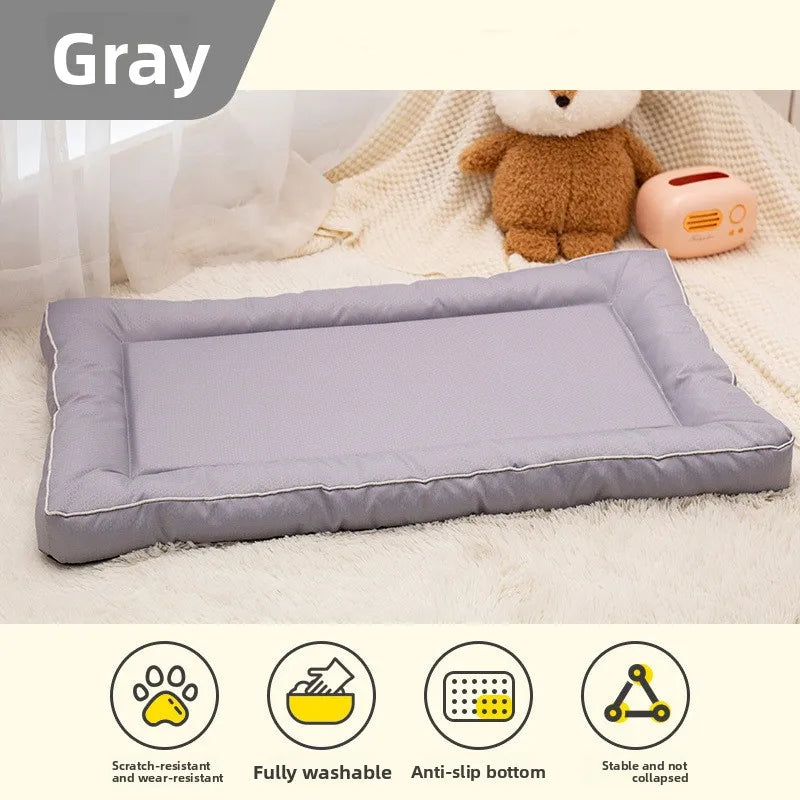 A gray chew-proof pet mat is shown on a white blanket with a teddy bear and a small pink device.