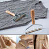 A manual lint remover brush is shown against a gray knitted sweater and fabric.